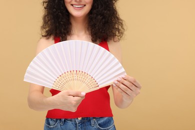 Photo of Woman holding hand fan on beige background, closeup. Space for text