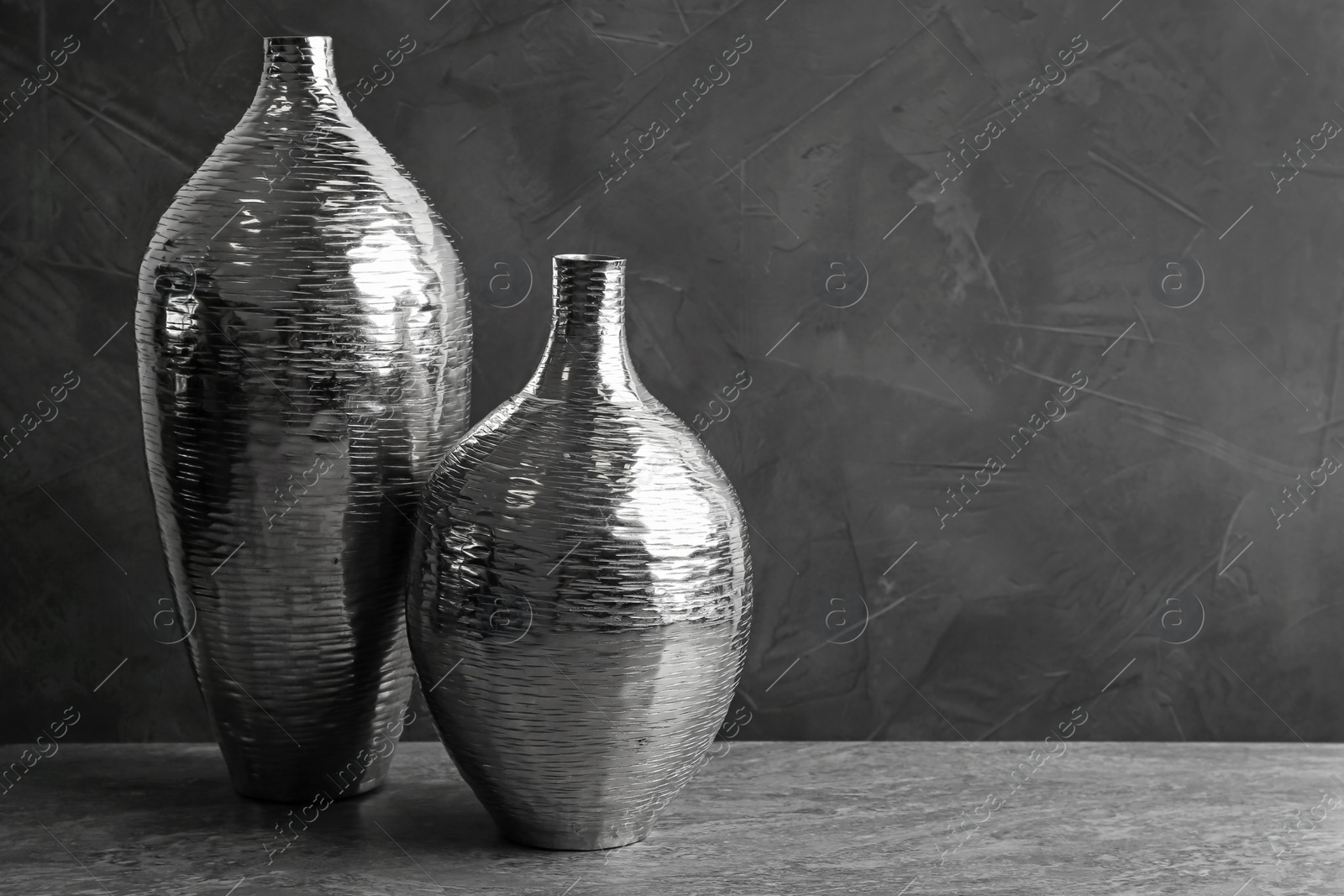 Photo of Stylish silver ceramic vases on grey table, space for text