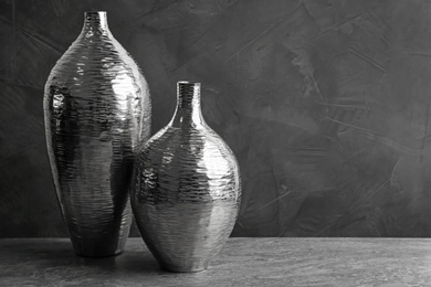 Photo of Stylish silver ceramic vases on grey table, space for text