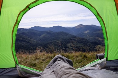 Photo of Grey sleeping bag in camping tent on hill, view from inside