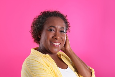 Portrait of happy African-American woman on pink background