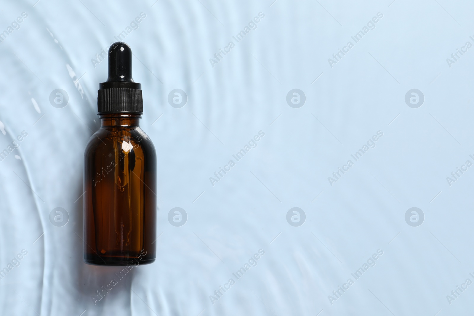 Photo of Bottle of cosmetic serum and water on light blue background, top view. Space for text