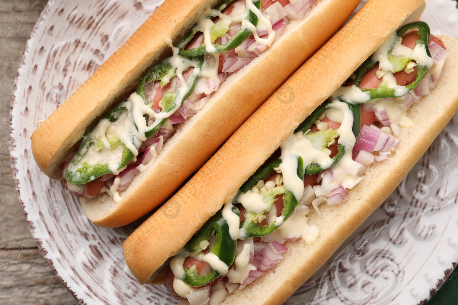 Photo of Delicious hot dogs with onion, chili pepper and sauce on table, top view