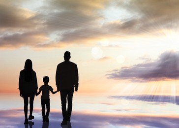 Image of Silhouettes of godparents with child and beautiful view of sky with clouds at sunset, space for text