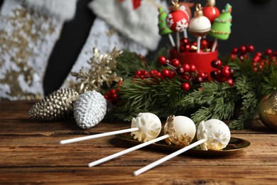 Photo of Delicious Christmas themed cake pops and festive decor on wooden table