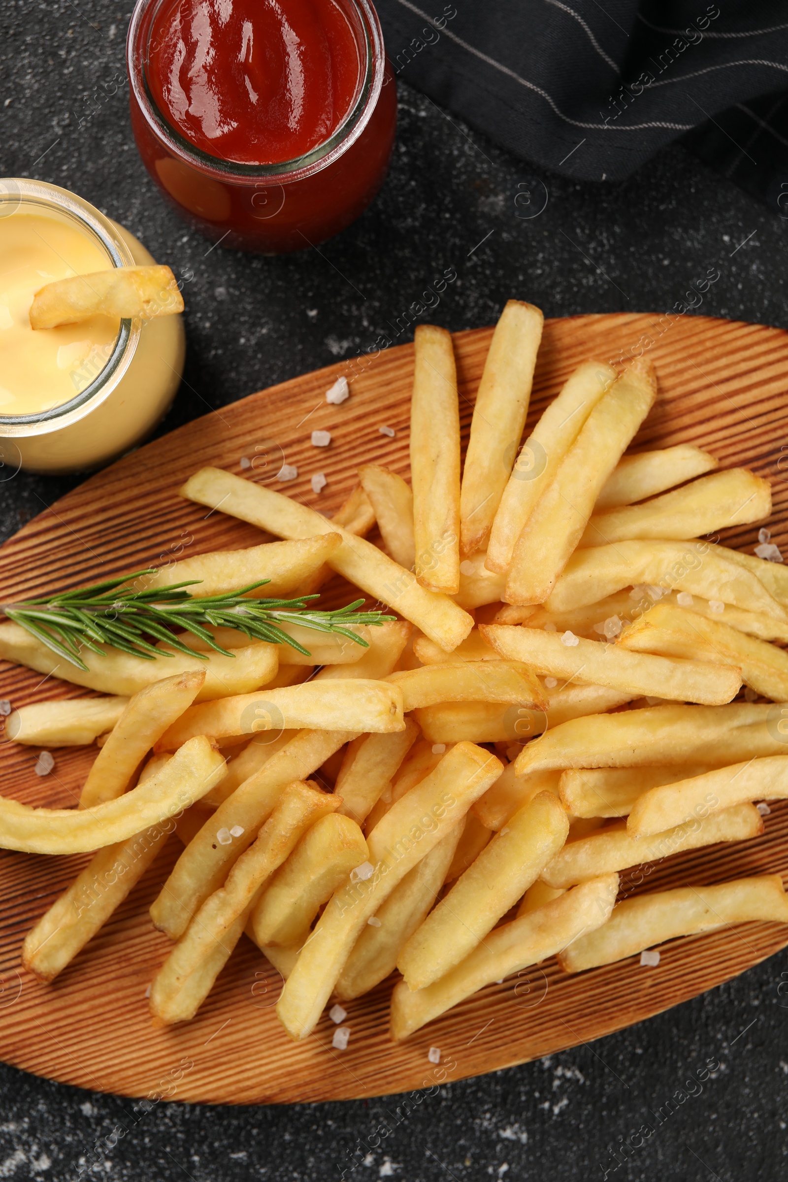 Photo of Delicious french fries served with sauces on grey textured table, flat lay