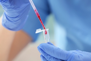 Scientist dripping blood into test tube in laboratory