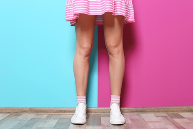 Young woman with sexy legs near color wall