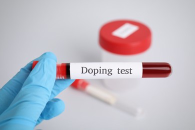 Doctor holding test tube with blood sample over table, closeup. Doping control
