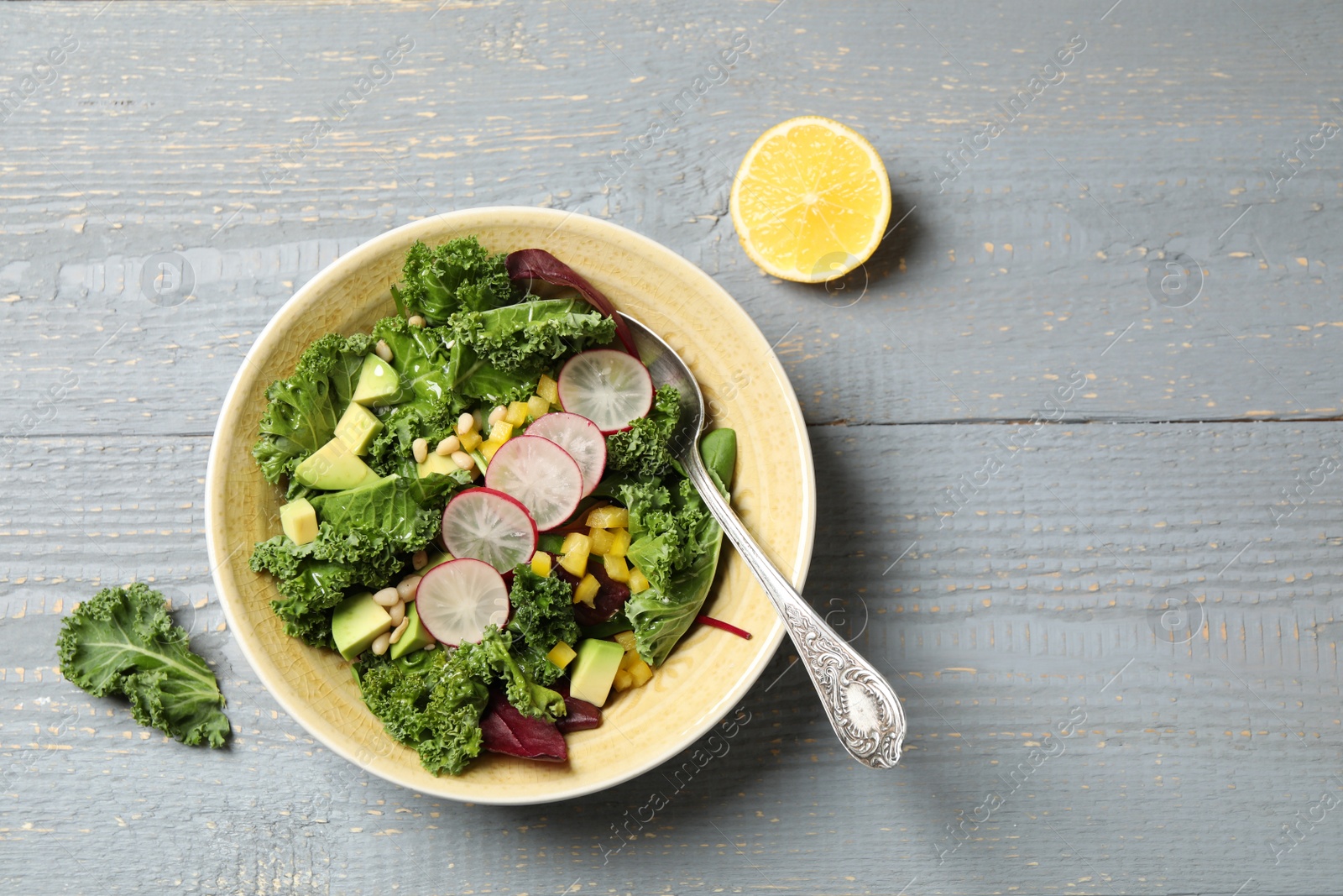 Photo of Delicious kale salad served on grey wooden table, flat lay