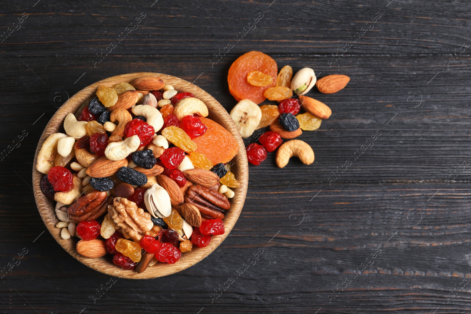 Photo of Bowl with different dried fruits and nuts on table, top view. Space for text