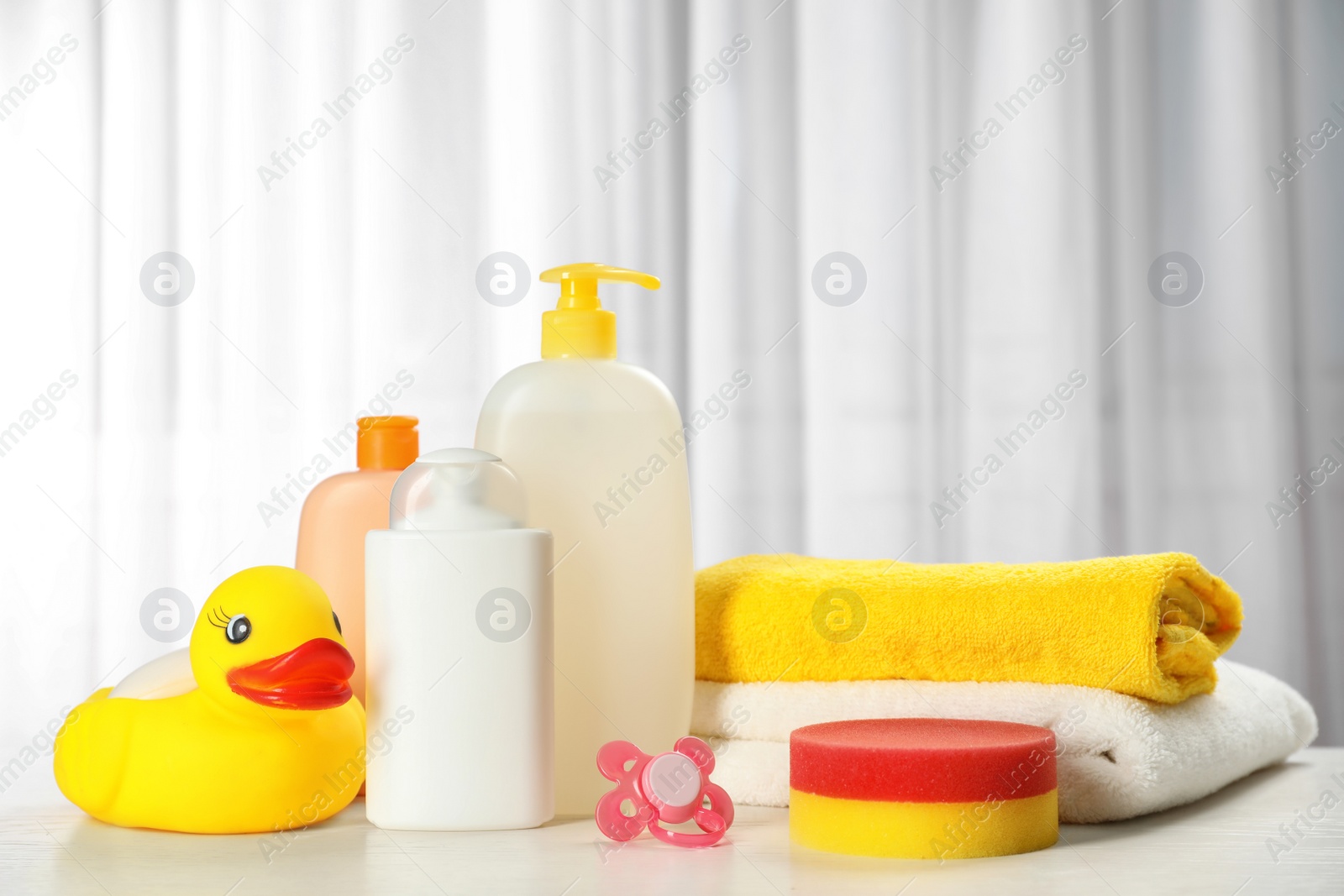 Photo of Baby cosmetic products, toy and towels on table indoors