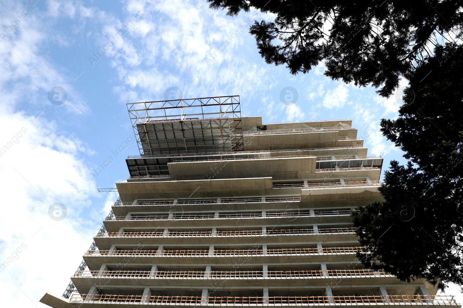 Photo of Multistory building under construction against cloudy sky, low angle view