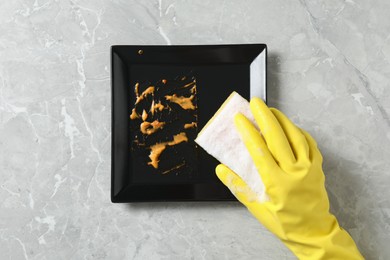 Woman washing dirty plate at grey marble table, top view