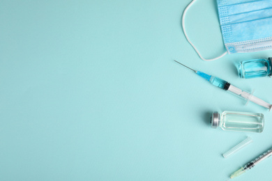 Photo of Vials, syringes and surgical mask on turquoise background, flat lay with space for text. Vaccination and immunization