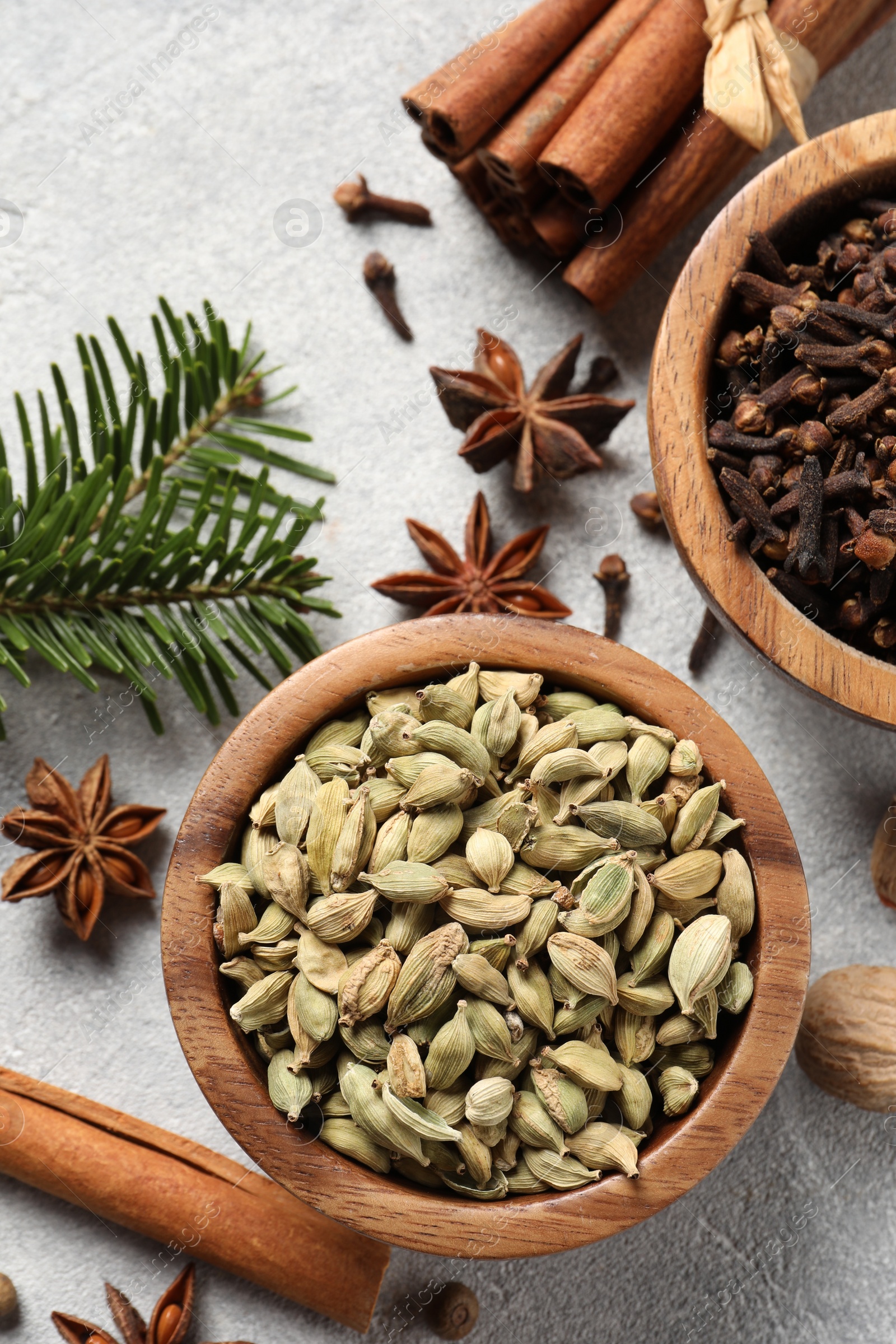 Photo of Different aromatic spices and fir branches on light textured table, flat lay