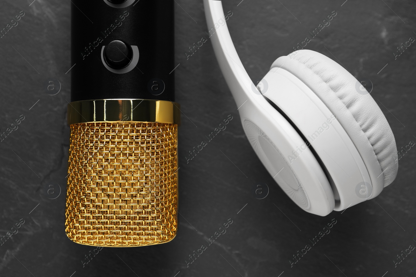 Photo of Microphone and headphones on grey textured background, flat lay. Sound recording and reinforcement