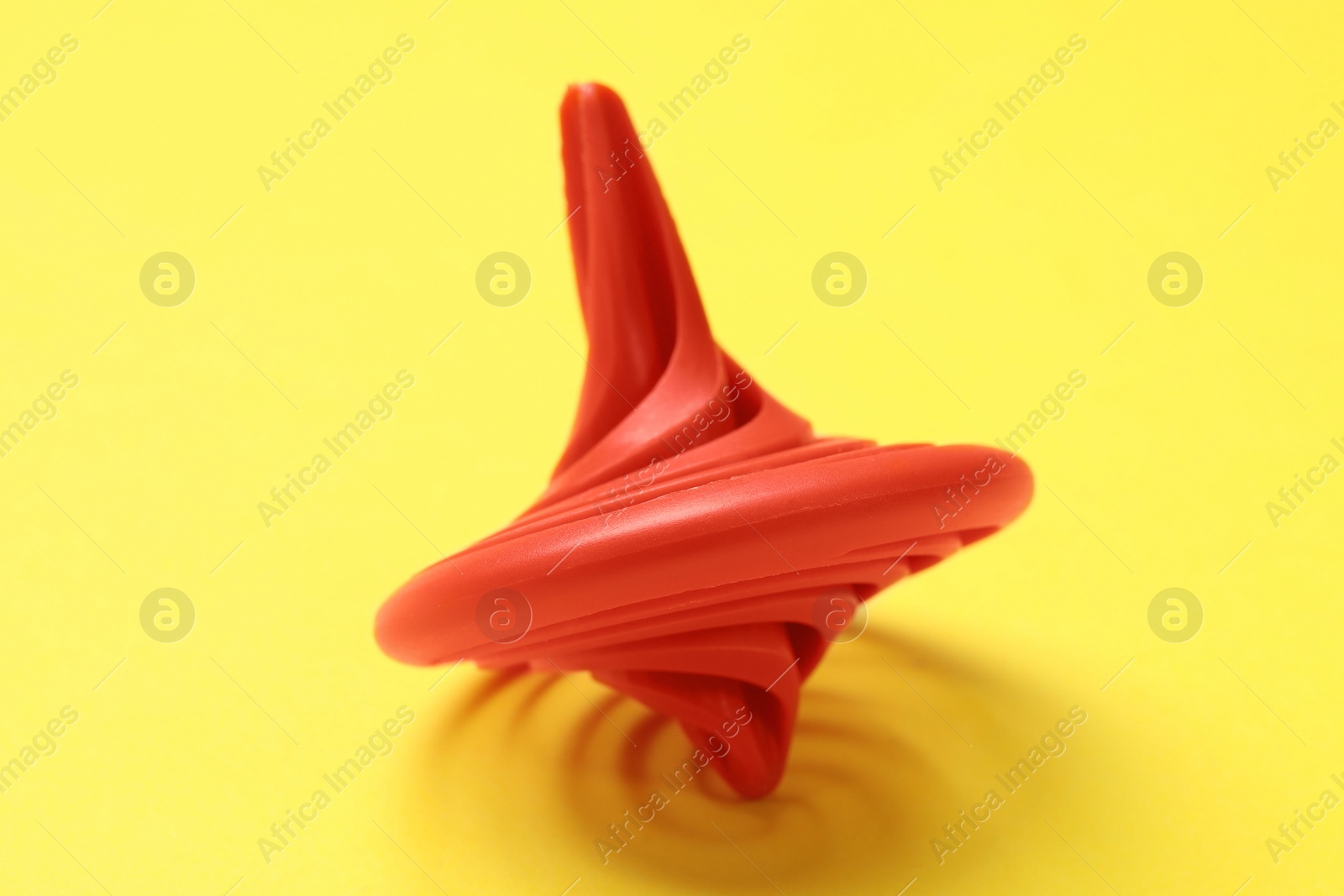 Photo of One red spinning top on yellow background, closeup