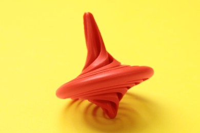 One red spinning top on yellow background, closeup