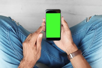 Man using smartphone with green screen, closeup. Gadget display with chroma key. Mockup for design