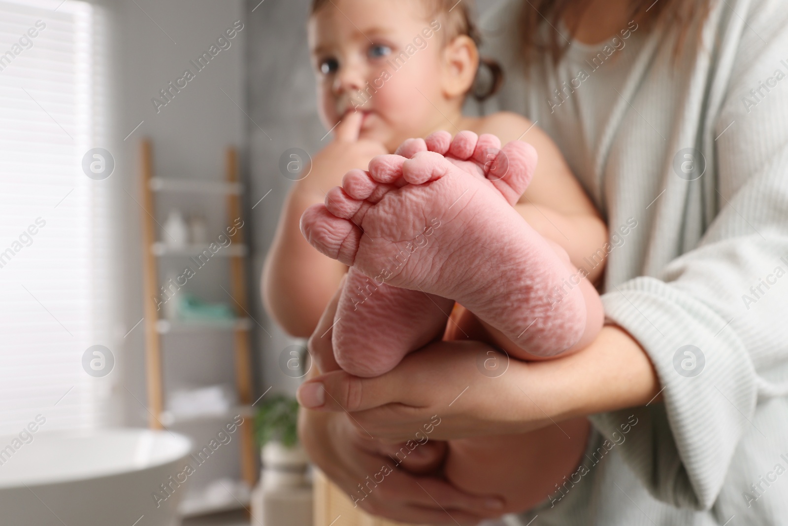 Photo of Mother with her daughter after bath at home, focus on child`s feet