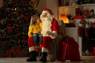 Photo of Merry Christmas. Little girl whispering her wish to Santa at home