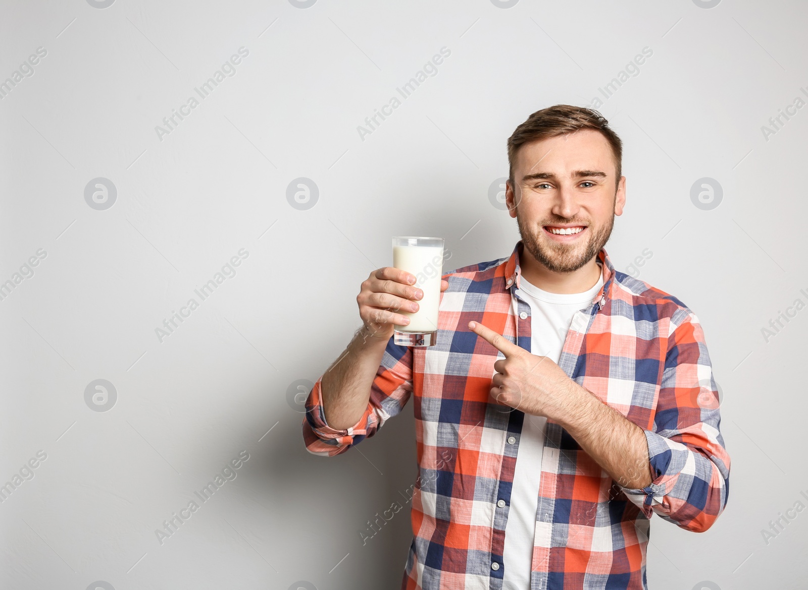 Photo of Young man with glass of tasty milk on light background