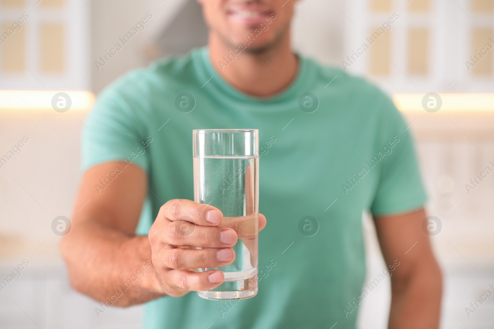 Photo of Man holding glass of pure water indoors, closeup