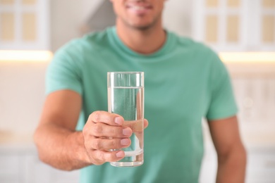 Man holding glass of pure water indoors, closeup