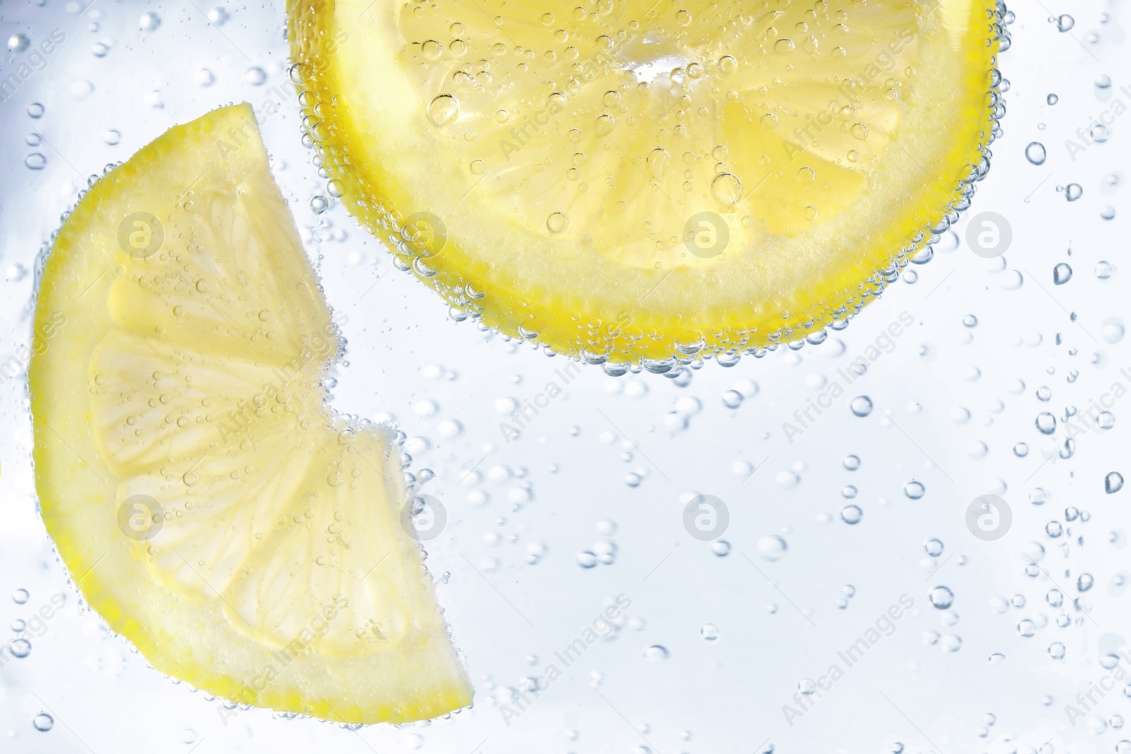 Photo of Juicy lemon slices in soda water, closeup