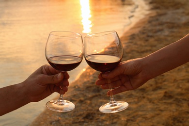 Photo of Romantic couple drinking wine together on beach, closeup view