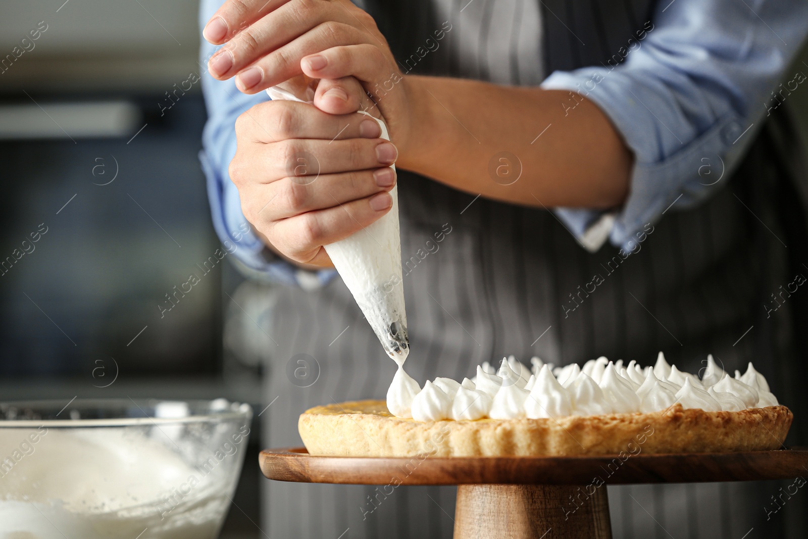 Photo of Woman preparing lemon meringue pie in kitchen, closeup