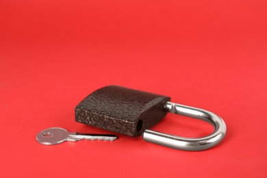 Photo of Modern padlock and key on red background. Space for text