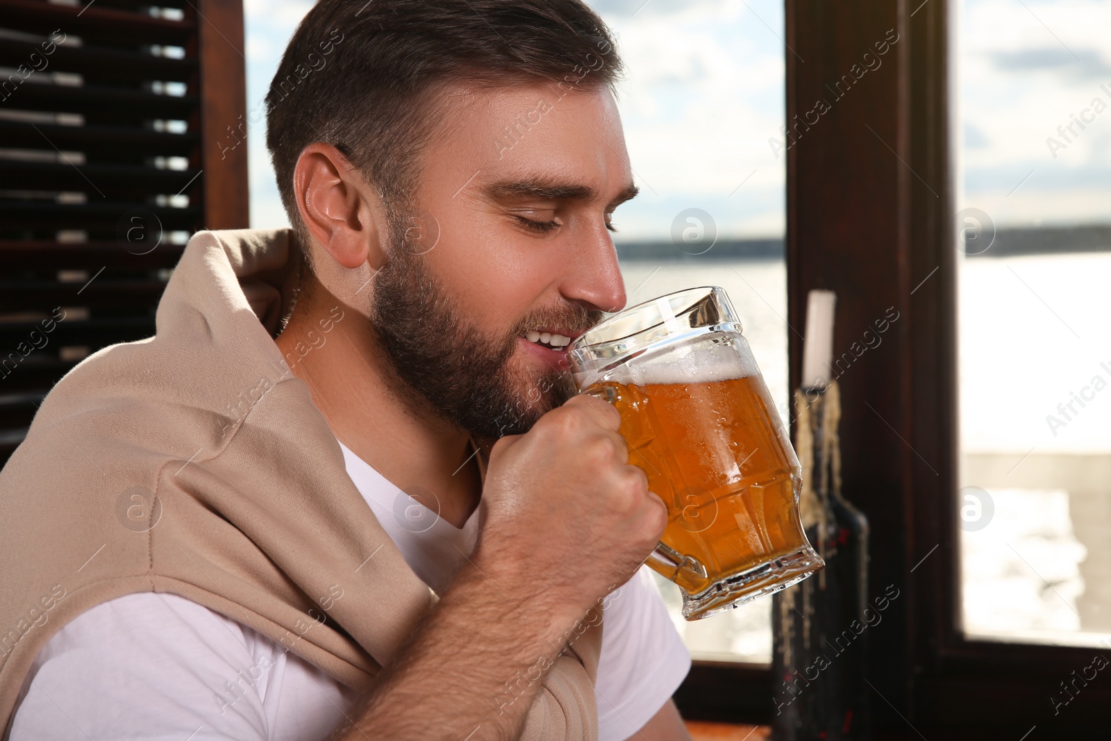 Photo of Young man drinking tasty beer in pub