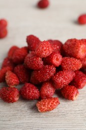 Photo of Pile of wild strawberries on white wooden table, closeup