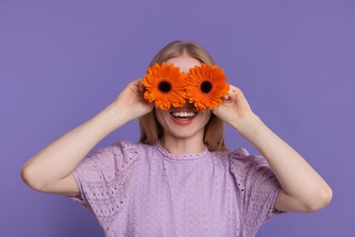 Woman covering her eyes with spring flowers on purple background
