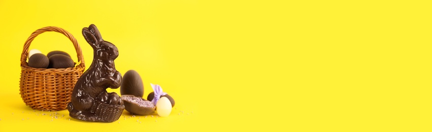 Photo of Chocolate Easter bunny and eggs on yellow background