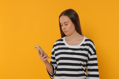 Teenage girl using smartphone on orange background