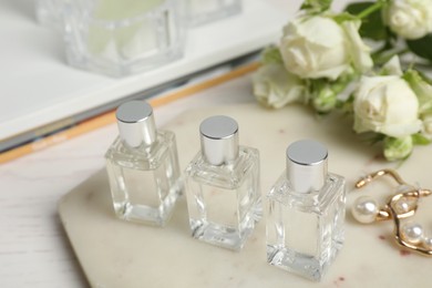 Perfumes and stylish earrings on white table