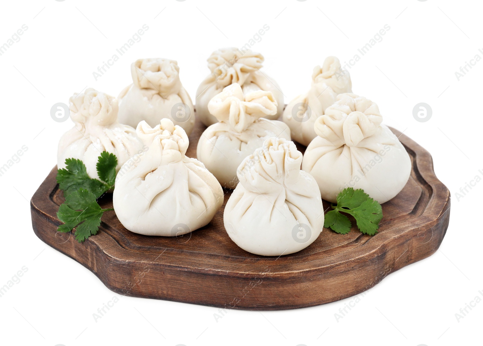 Photo of Wooden board with uncooked khinkali (dumplings) and parsley isolated on white. Georgian cuisine