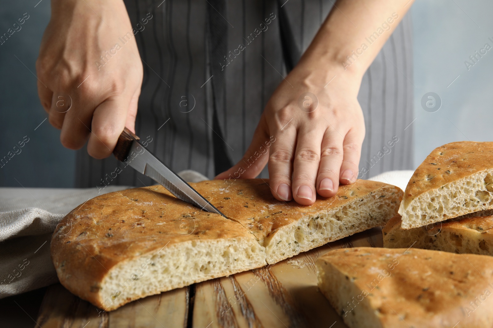 Photo of Woman cutting bread on wooden board, closeup