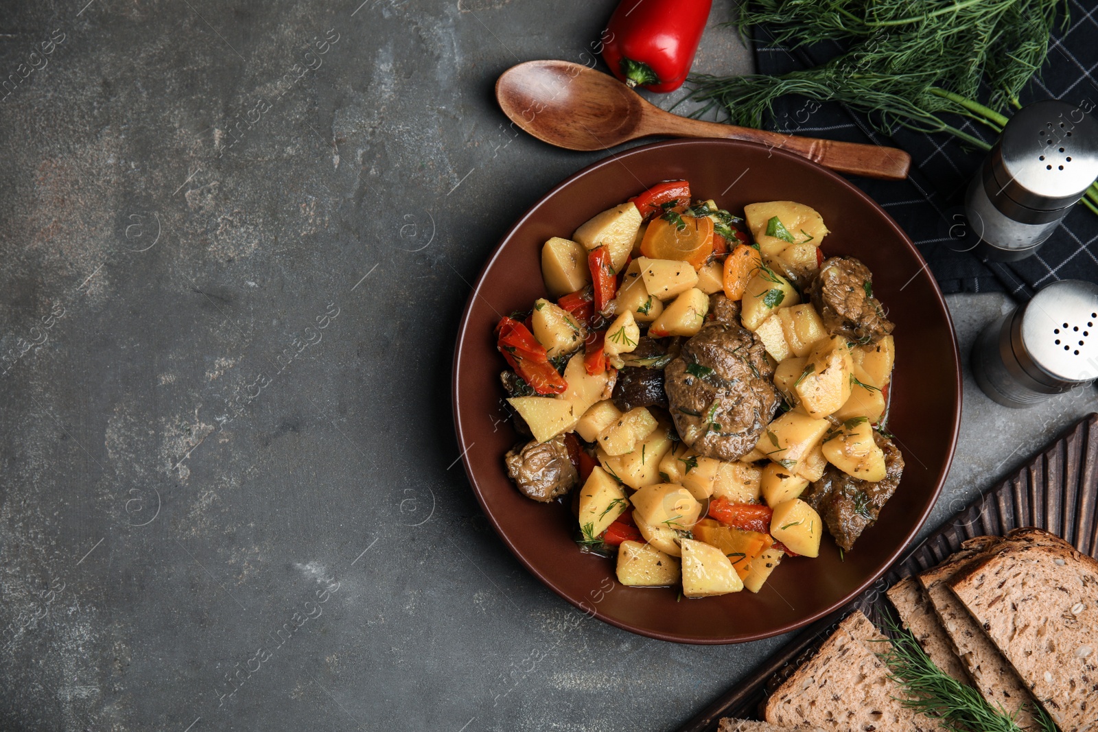 Photo of Tasty cooked dish with potatoes in earthenware served on grey table, flat lay. Space for text