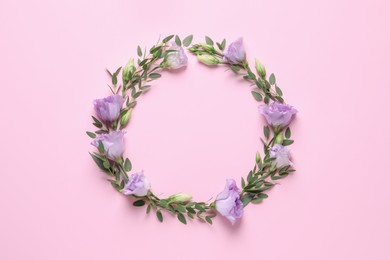 Photo of Wreath made of beautiful flowers and green leaves on pink background, flat lay. Space for text