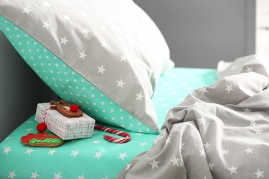 Gift box with candy cane and gingerbread under pillow in children's bedroom. St. Nicholas Day tradition