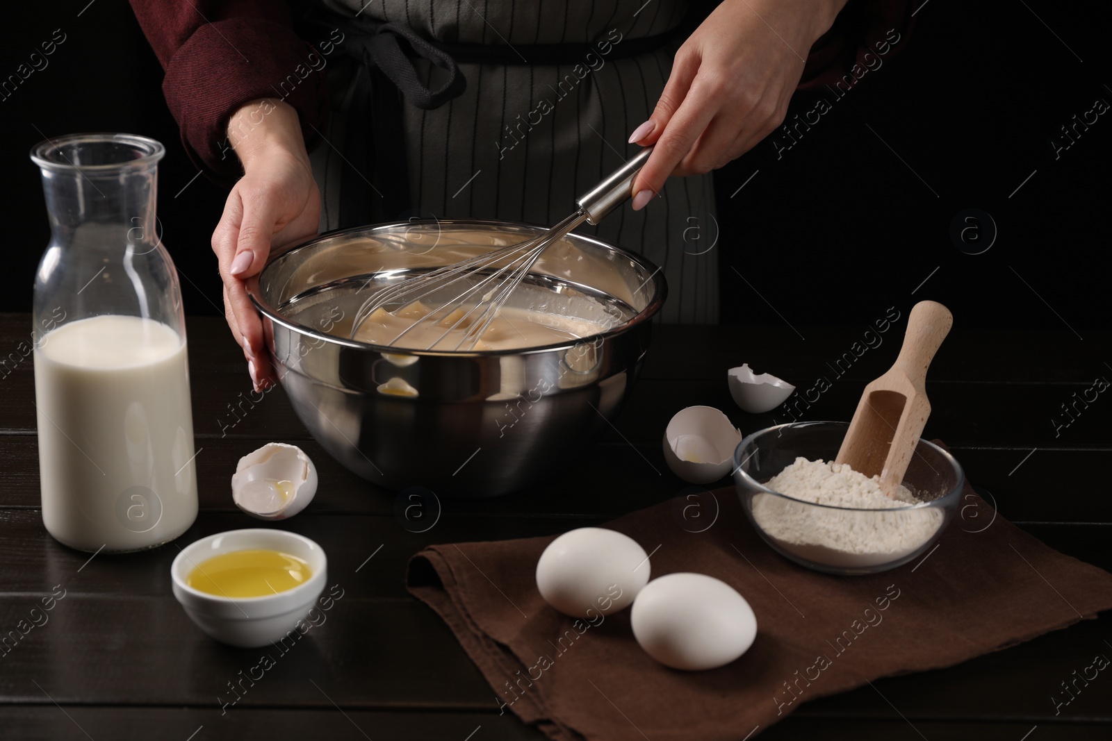 Photo of Woman making dough with whisk in bowl at table, closeup