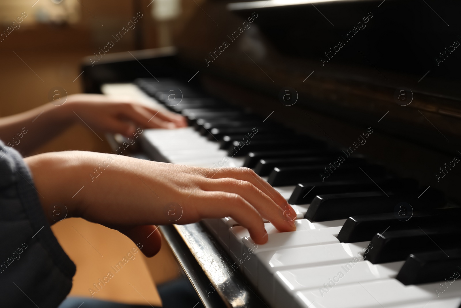 Photo of Little child playing piano, closeup. Music lesson