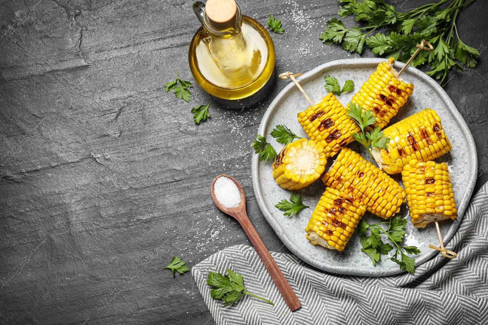 Photo of Delicious grilled corn cobs on grey table, flat lay. Space for text