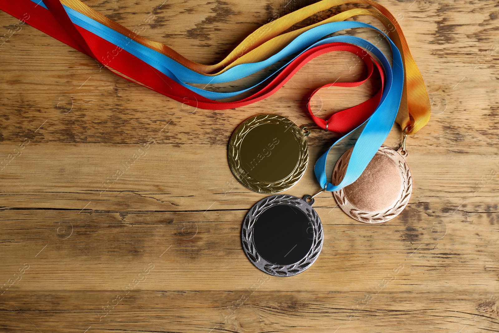 Photo of Gold, silver and bronze medals on wooden background, flat lay. Space for design