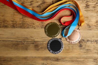 Gold, silver and bronze medals on wooden background, flat lay. Space for design