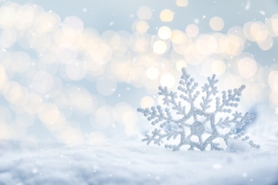 Beautiful decorative snowflake on white snow. Space for text